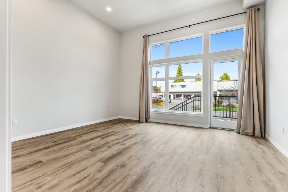 Large room with wood floors and full wall of tall windows and balcony door at Cartwright Apartments in Salem, Oregon