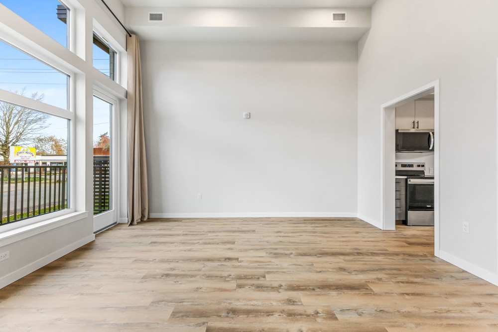 Open room with tall windows, light walls, and entry to kitchen at Cartwright Apartments in Salem, Oregon