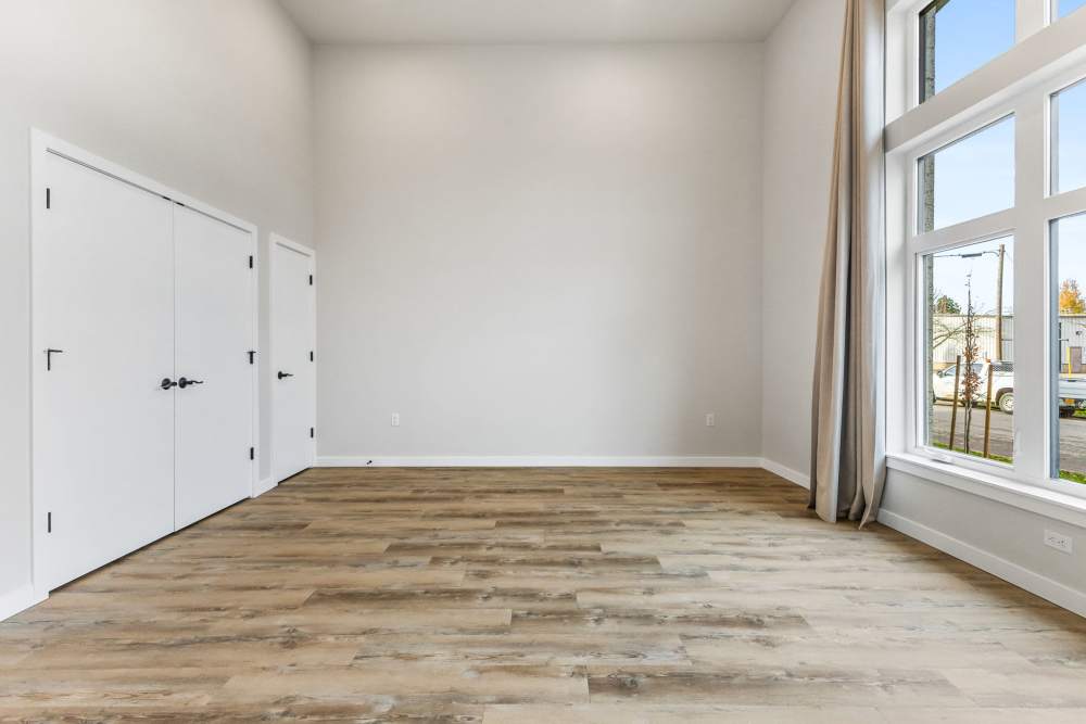Spacious room with wood floors, double closets, and large front windows at Cartwright Apartments in Salem, Oregon