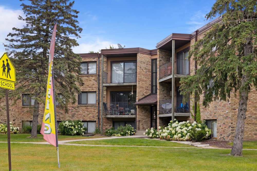 Apartment exterior view with lush green garden at Fountain Terrace in New Brighton, Minnesota