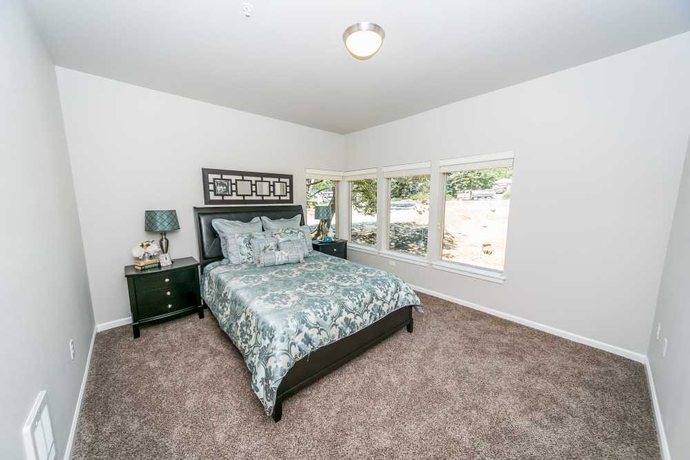 Bedroom with patterned bedding, nightstands, and wide windows at Columbia View in Vancouver, Washington