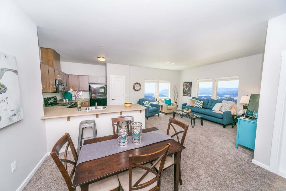 Open layout of dining, kitchen, and living room with bright windows at Columbia View in Vancouver, Washington