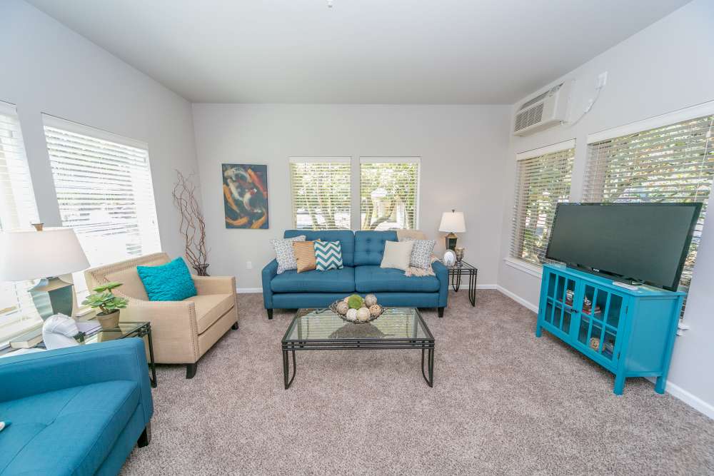 Living room with blue sofa, accent chairs, and large windows at Columbia View in Vancouver, Washington