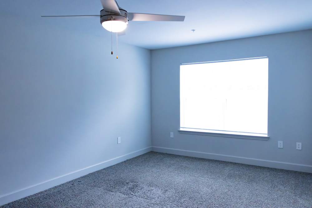 Bedroom with ceiling fan and large window at Villas At Mount Zion in Stockbridge, Georgia