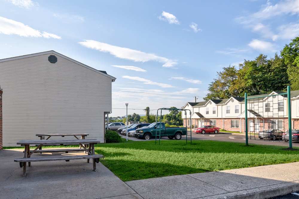 Picnic table on grassy area with parking lot and apartment buildings in background at Muirwood Greene in Romney, West Virginia
