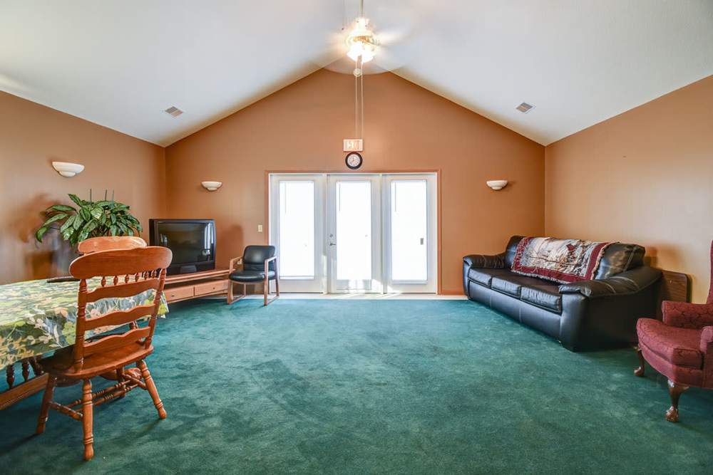 Clubhouse with green carpet, dining table, and large windows for natural light at Muirwood Greene in Romney, West Virginia