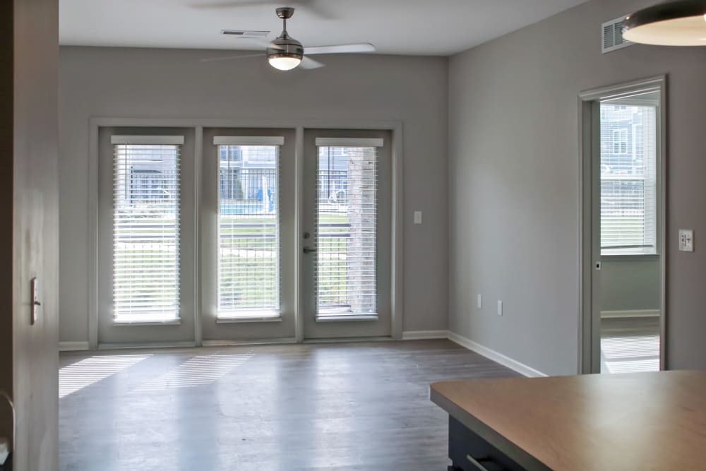Bright living area with wood-style flooring and large windows leading to a patio at Jefferson's Landing in Louisville, Kentucky