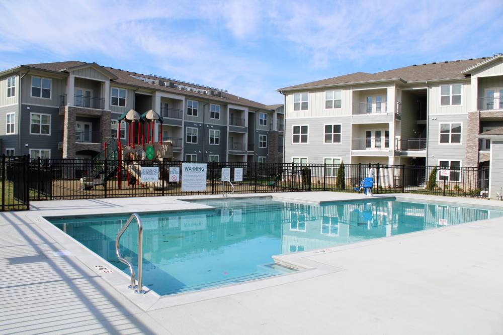 Resort-style pool with playground and gated entrance to apartment community at Jefferson's Landing in Louisville, Kentucky