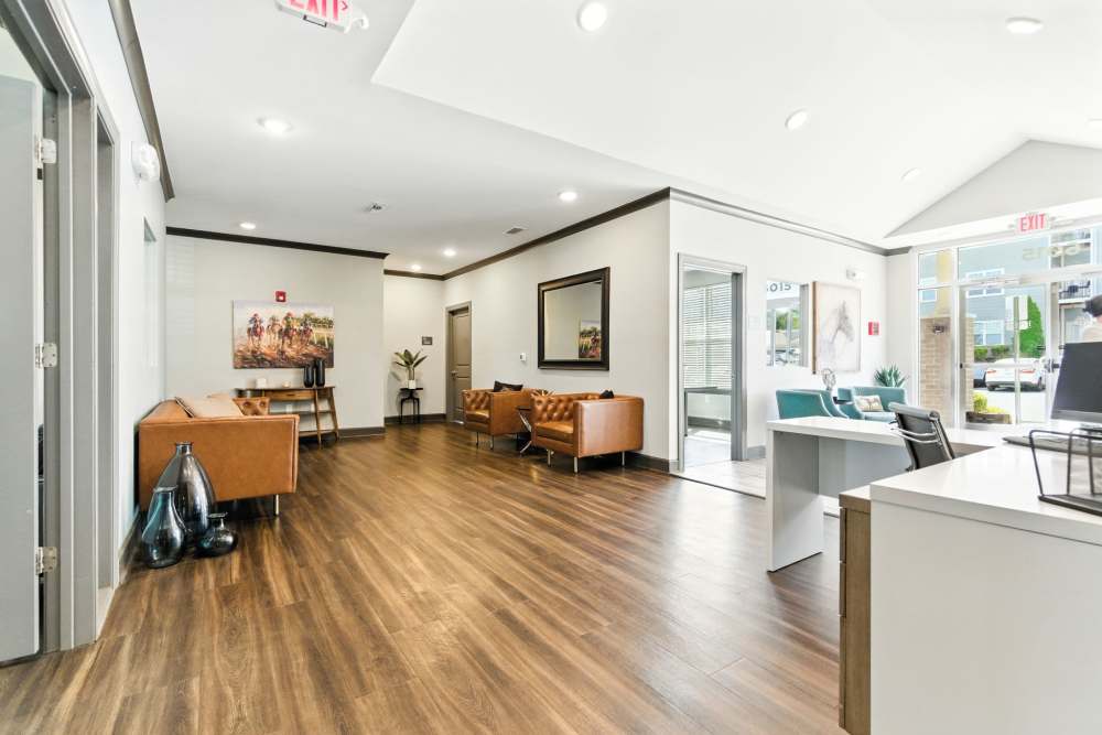 Modern lobby with wood-style flooring, comfortable seating, and natural light from large windows at Bristol Bluffs Apartments in Louisville, Kentucky
