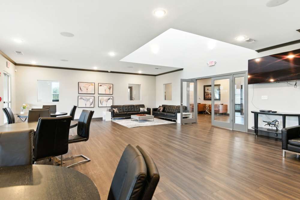 Modern community lounge with wood-style flooring, comfortable seating, and large TV for gatherings at Bristol Bluffs Apartments in Louisville, Kentucky