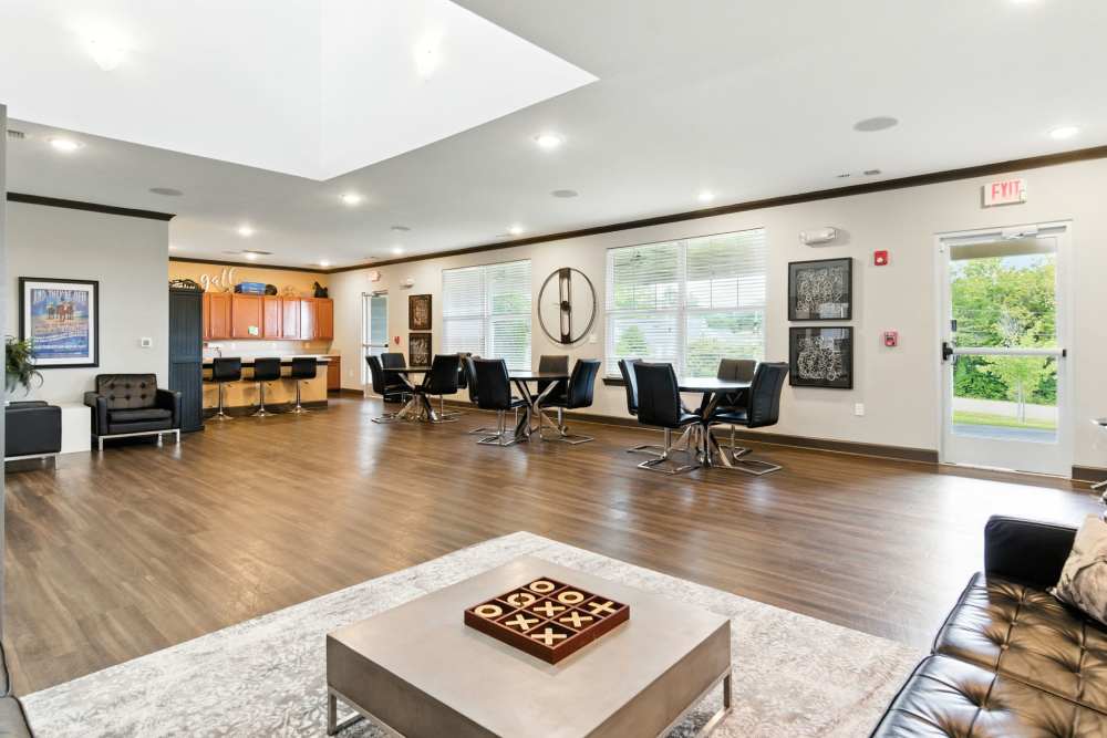 Modern community lounge with wood-style flooring, seating areas, and a kitchenette with bar stools at Bristol Bluffs Apartments in Louisville, Kentucky