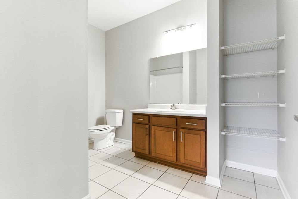 Spacious bathroom with wooden vanity, large mirror, and tiled flooring at Bristol Bluffs Apartments in Louisville, Kentucky