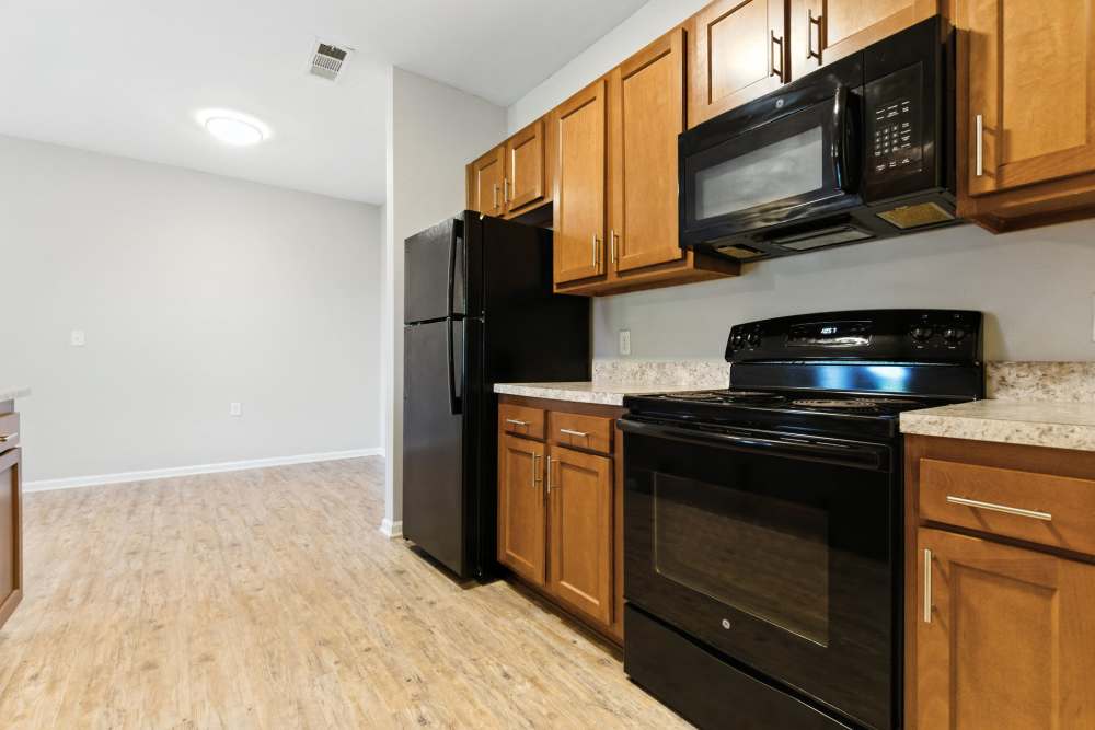 Modern kitchen with granite countertops, stainless steel appliances, and wood-style flooring at Bristol Bluffs Apartments in Louisville, Kentucky