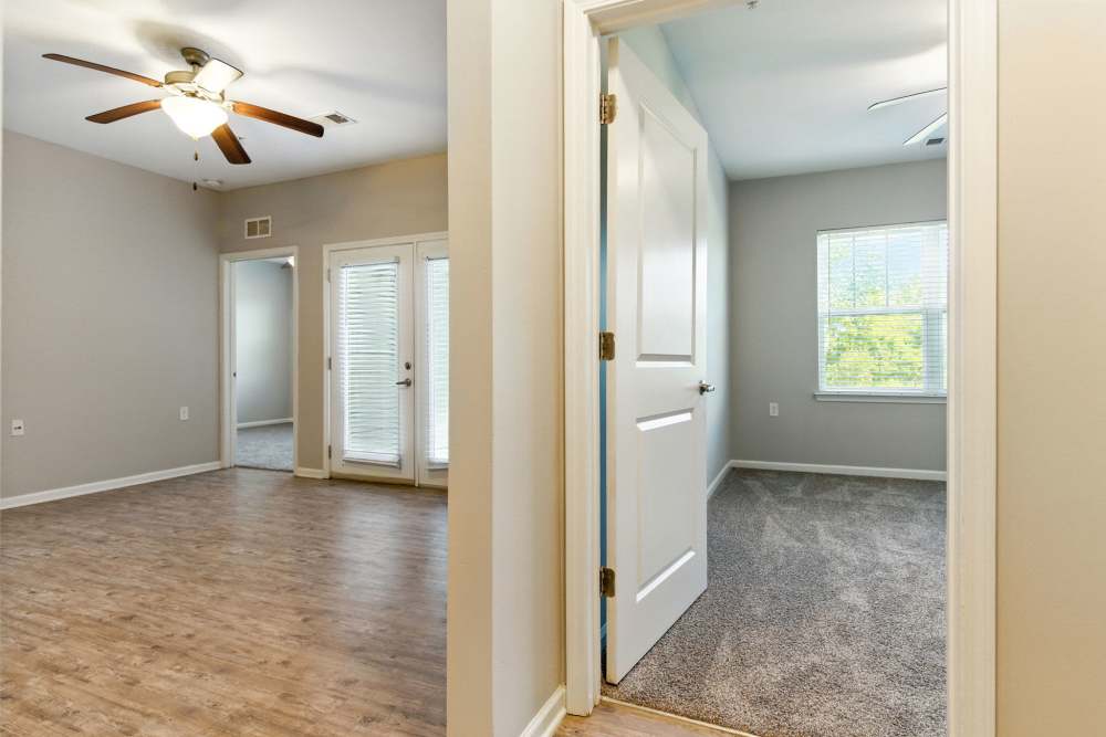 Open layout with wood-style flooring, ceiling fan, and natural light from patio doors at Bristol Bluffs Apartments in Louisville, Kentucky
