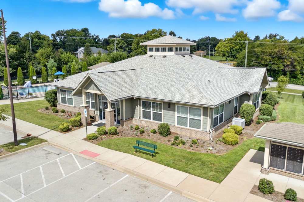 Community clubhouse with landscaped grounds and seating area near a sparkling pool at Bristol Bluffs Apartments in Louisville, Kentucky