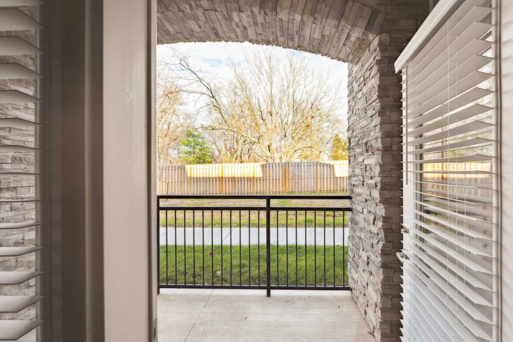 Balcony view with stone accents and grassy area beyond the railing at Lone Oak Meadows in Louisville, Kentucky