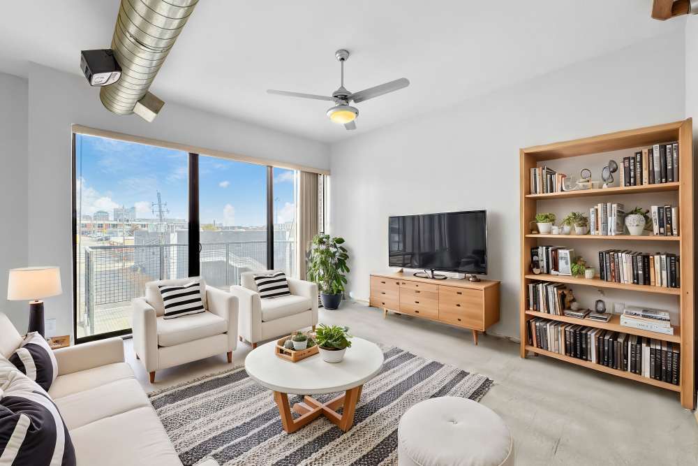 Bright living room with large windows, modern furniture, and a cozy atmosphere at Ingersoll Square in Des Moines, Iowa