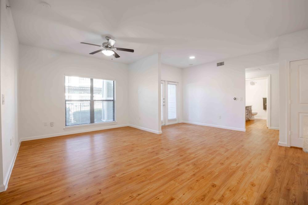 Open-concept living room in Austin, Texas with large windows and natural light-filled hardwood floors.