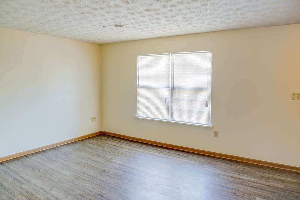 Spacious living area with wood-style flooring and large windows for natural light at Arlington Greene in London, Kentucky