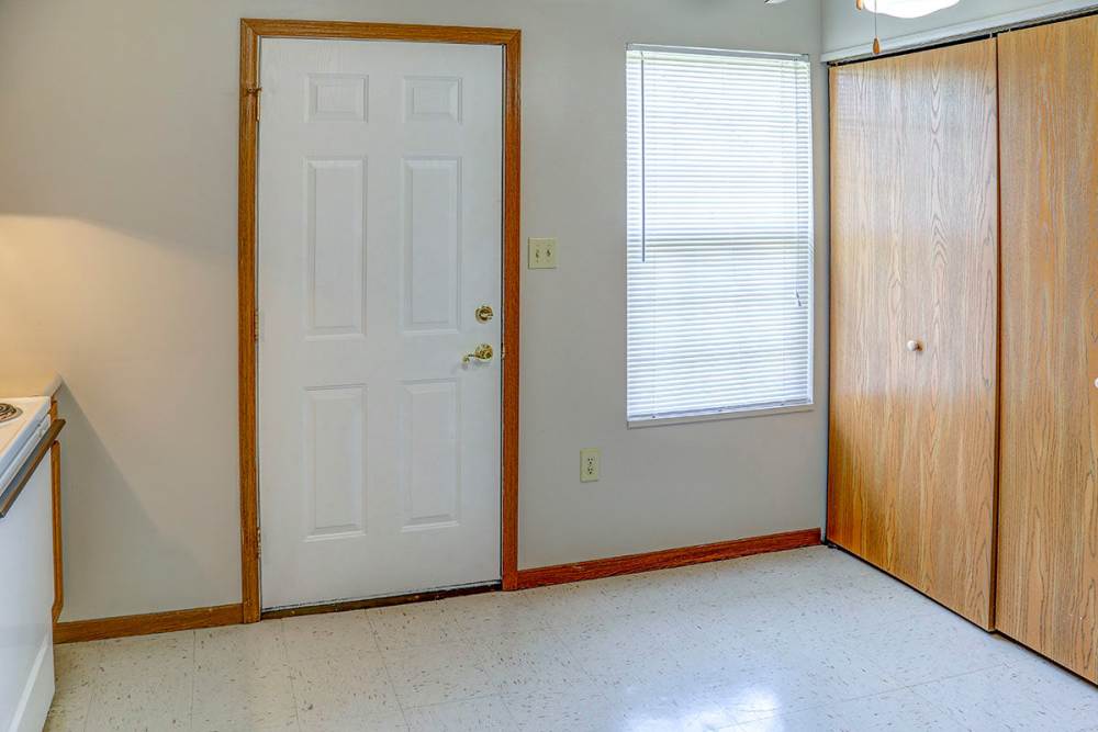 Bright entryway with a white door, window, and wooden closet doors at Arlington Terrace in London, Kentucky