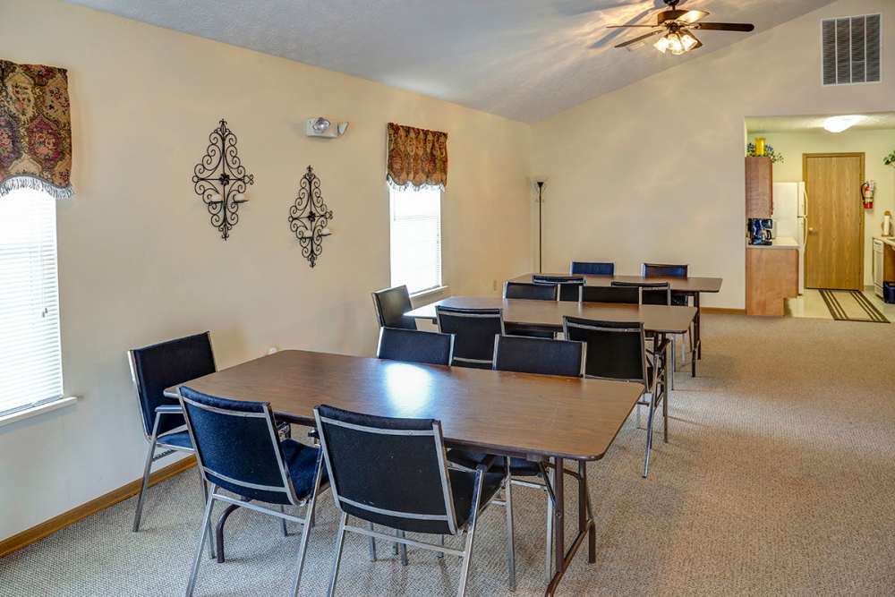 Community room with tables and chairs, large windows, and access to a kitchen area at Arlington Terrace in London, Kentucky