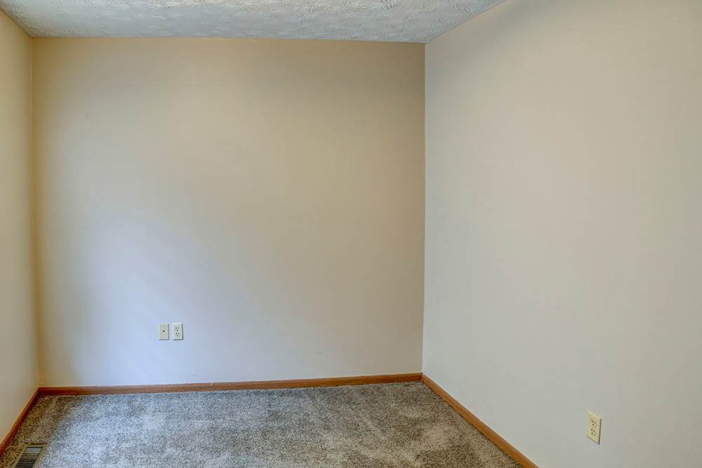 Empty room with beige walls and carpeted flooring, ready for personalization at Arlington Terrace in London, Kentucky