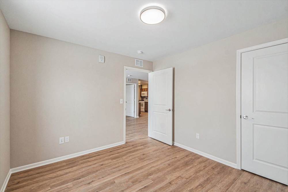 Open layout with wood-style flooring and light-colored walls, kitchen visible through doorway at Breton Grove II in Grand Rapids, Michigan