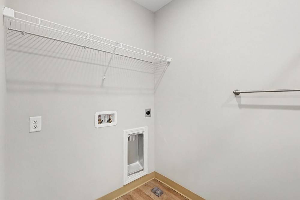 Laundry room with wire shelving, washer and dryer hookups, and pet door for furry friends at Bridlewood Crossing in Louisville, Kentucky