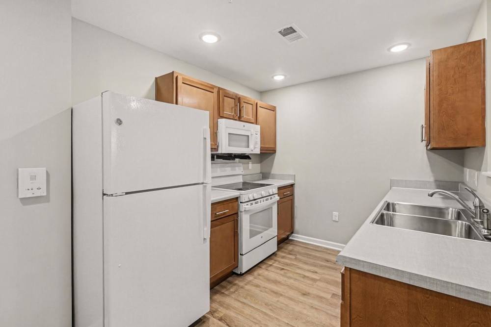 Modern kitchen with stainless steel appliances and wood-style flooring at Bridlewood Crossing in Louisville, Kentucky