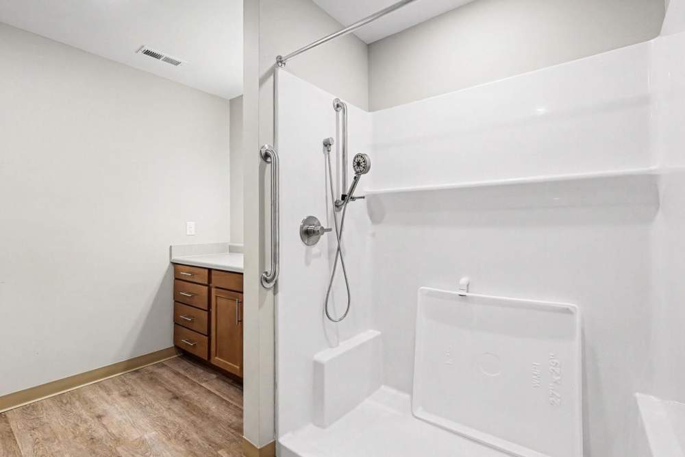 Modern bathroom with walk-in shower, wood-style flooring, and wooden cabinetry at Bridlewood Crossing in Louisville, Kentucky
