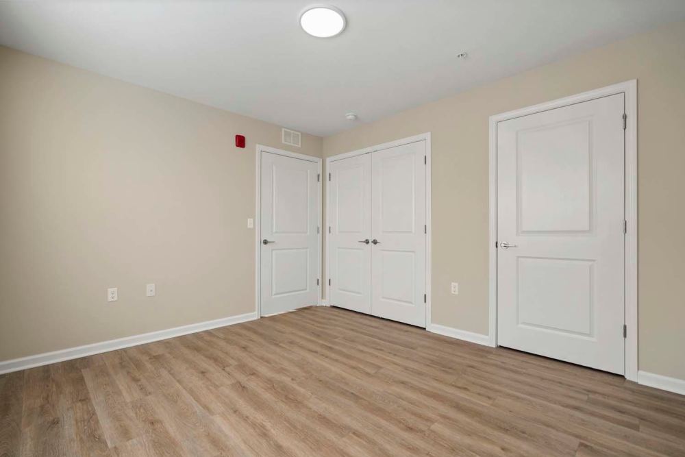 Spacious room with wood-style flooring and neutral walls, featuring two closed doors and a ceiling light at Edison Crossing in Mount Clemens, Michigan