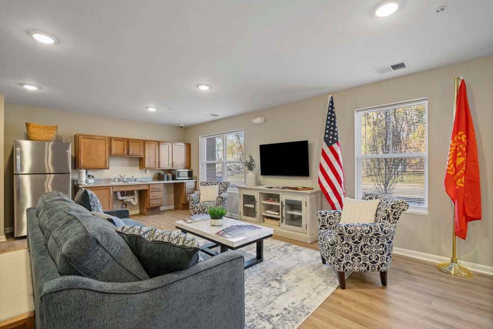 Open layout living area with wood-style flooring, stainless steel appliances, and cozy seating options at Edison Crossing in Mount Clemens, Michigan
