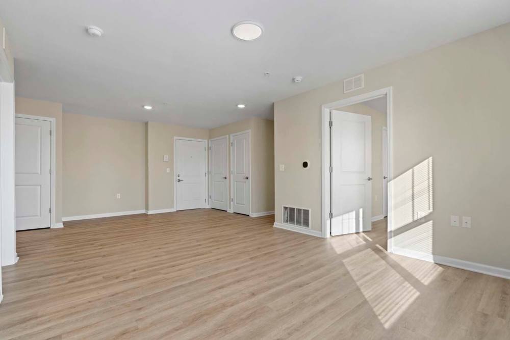 Spacious living area with wood-style flooring and natural light from windows at Edison Crossing in Mount Clemens, Michigan