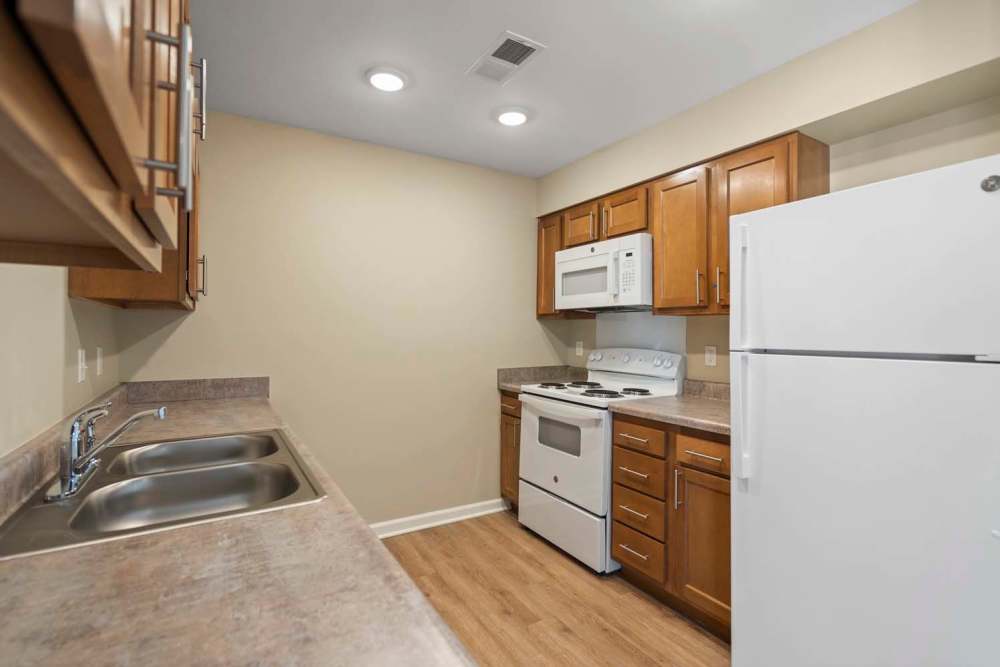 Modern kitchen with granite countertops, stainless steel appliances, and wood-style flooring at Edison Crossing in Mount Clemens, Michigan
