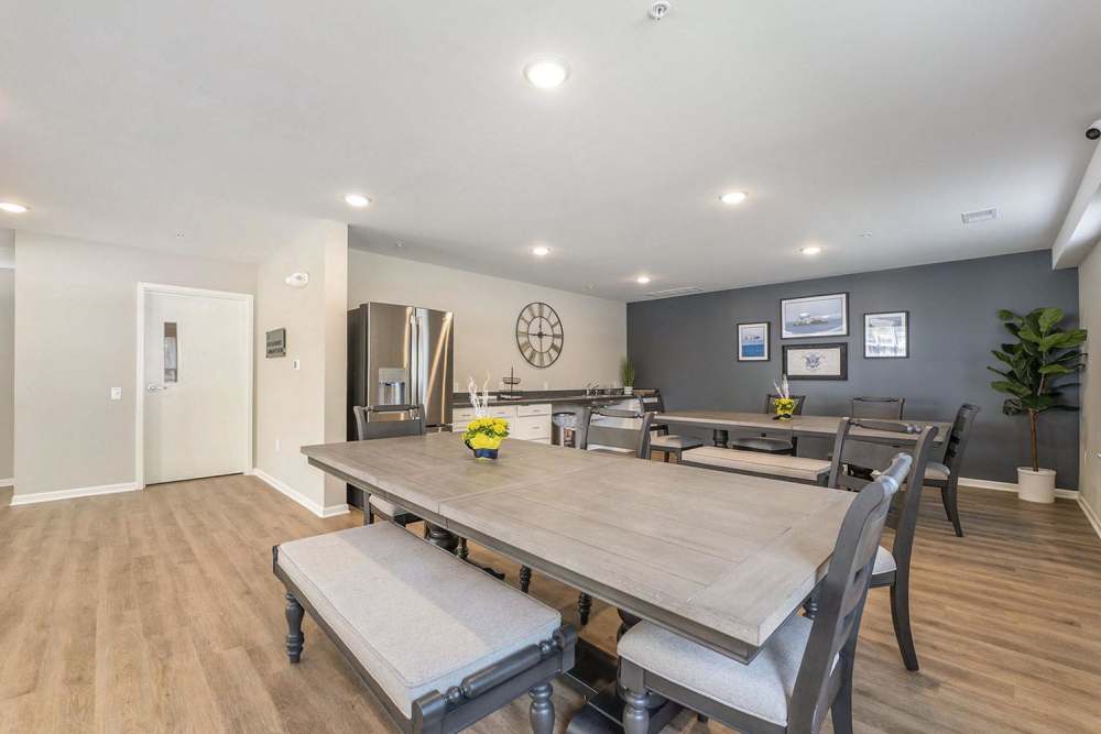 Modern dining area with wood-style flooring, large table, and stainless steel appliances in the kitchen at Annika Place in Traverse City, Michigan