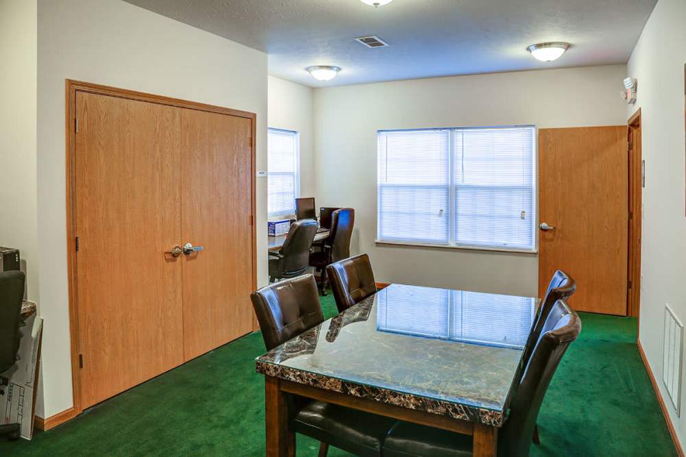 Dining area with a marble table and leather chairs, green carpet, and two doors leading to other rooms at Mason Greene in Monticello, Kentucky