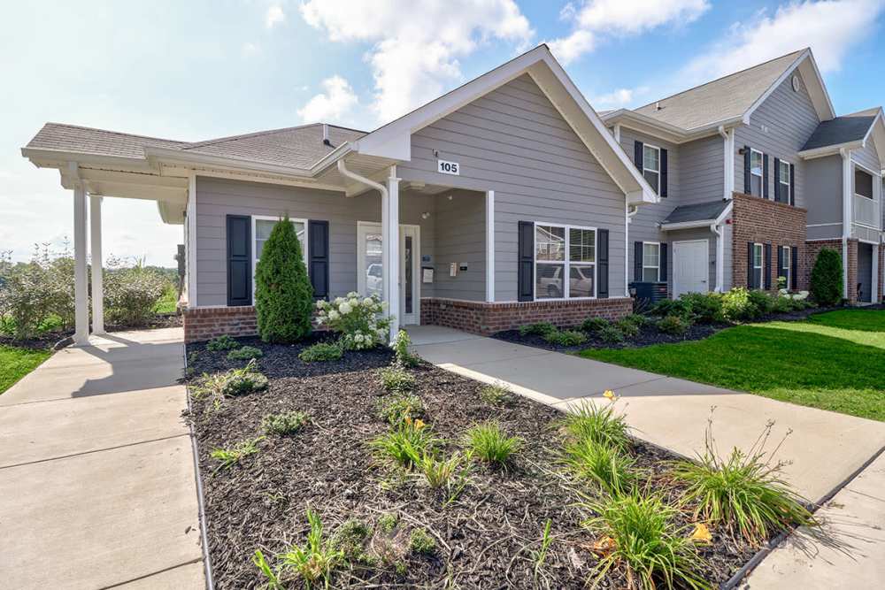 Welcoming apartment entrance with landscaped garden and pathway, bright exterior, and covered porch at Oliver Crossing in Linden, Tennessee