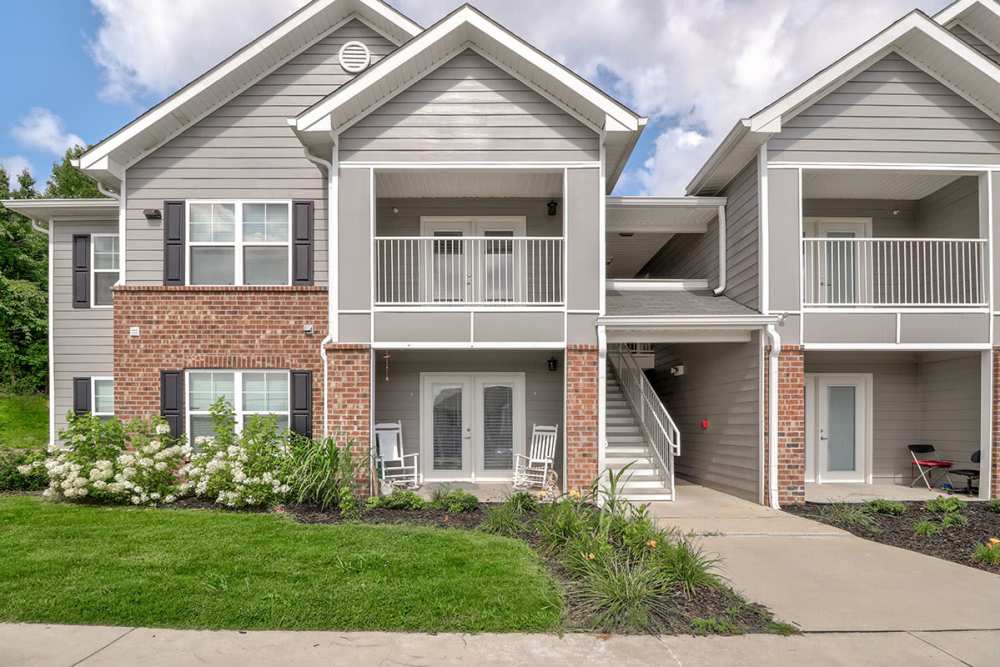 Two-story apartment community with balconies, landscaped gardens, and a welcoming entrance pathway at Oliver Crossing in Linden, Tennessee