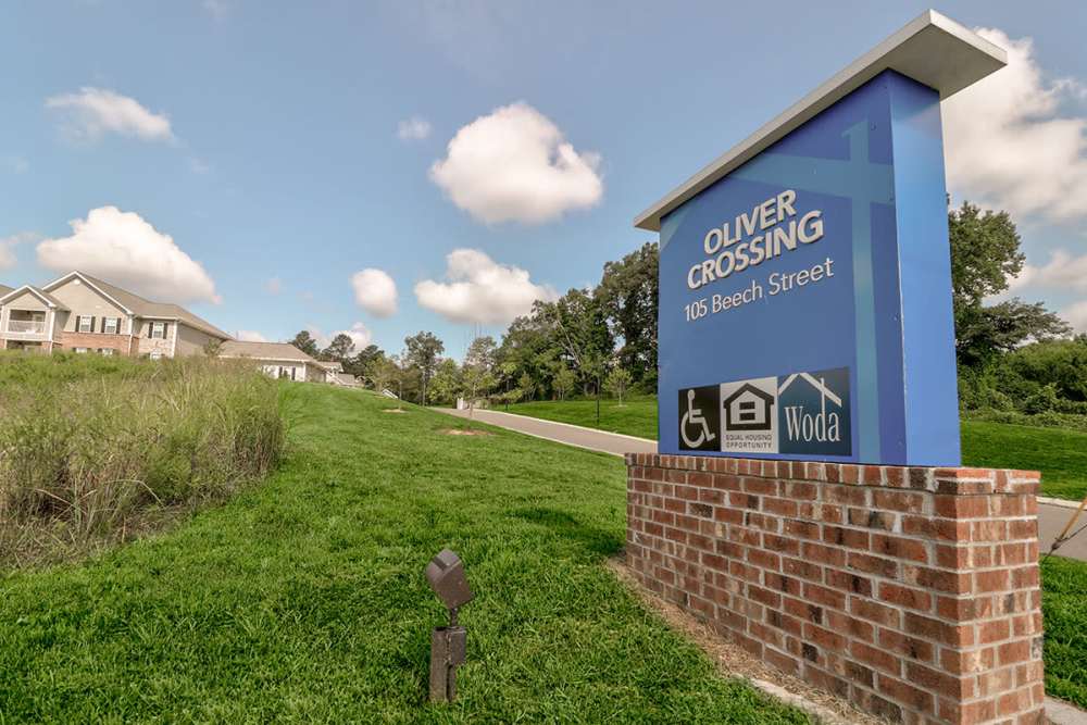 Sign for Oliver Crossing apartment community with green grass and blue sky in the background at Oliver Crossing in Linden, Tennessee