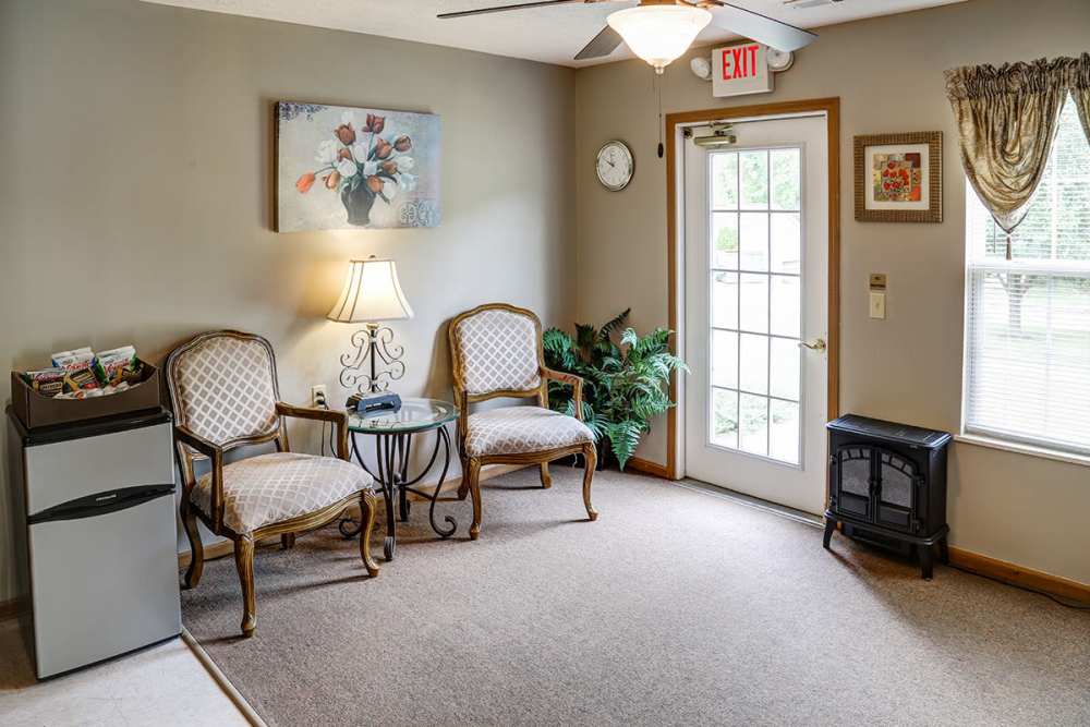 Cozy lobby with two chairs, small table, and a mini fridge by the door at Paint Landing in Stambaugh, Kentucky