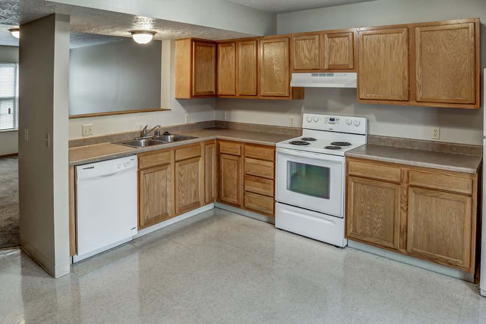 Bright kitchen with wood-style cabinets, white appliances, and spacious countertops at Paint Lick Station in Stambaugh, Kentucky