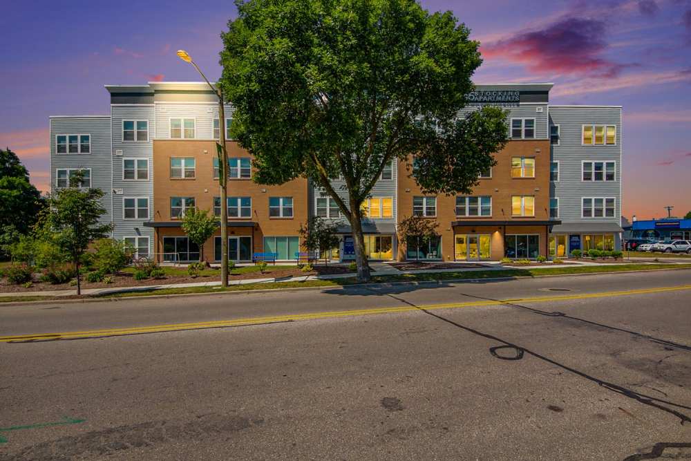 Modern apartment community with landscaped grounds and large windows at sunset at Seven45 Stocking in Grand Rapids, Michigan