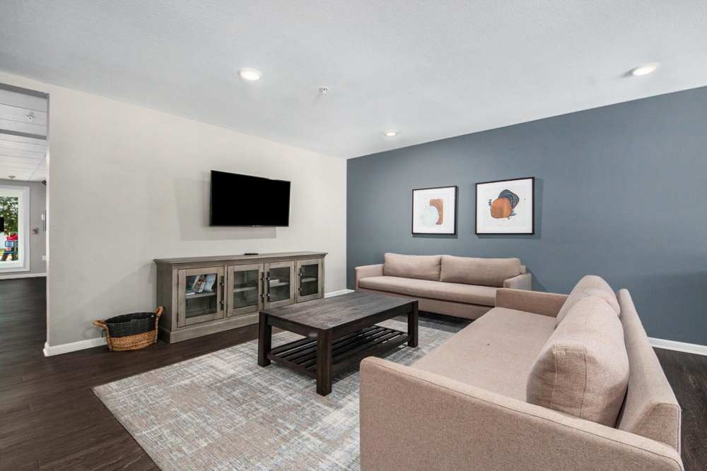 Modern lounge area with wood-style flooring, two sofas, coffee table, and wall-mounted TV at Seven45 Stocking in Grand Rapids, Michigan