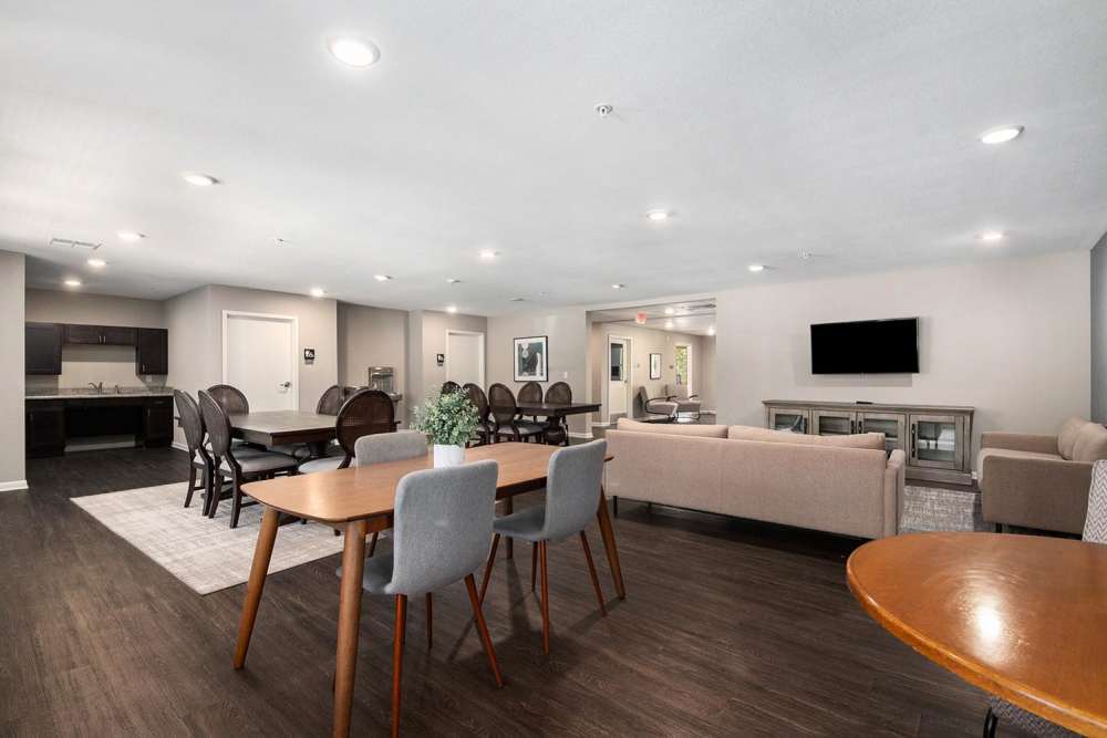 Modern community lounge with wood-style flooring, dining area, and kitchen featuring dark cabinetry and granite countertops at Seven45 Stocking in Grand Rapids, Michigan
