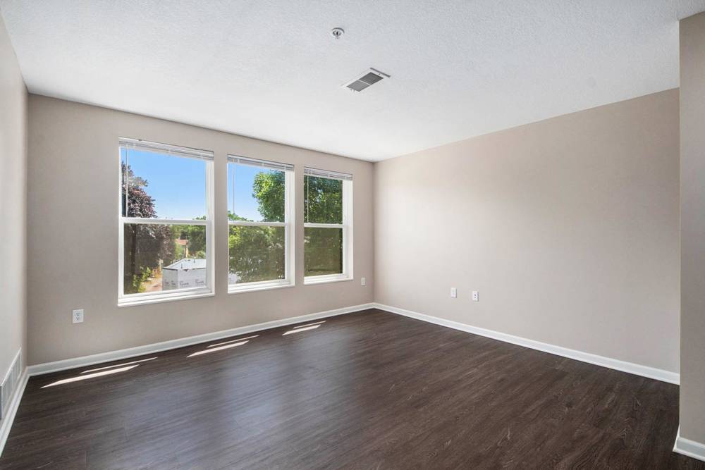 Spacious living area with wood-style flooring and large windows for natural light at Seven45 Stocking in Grand Rapids, Michigan