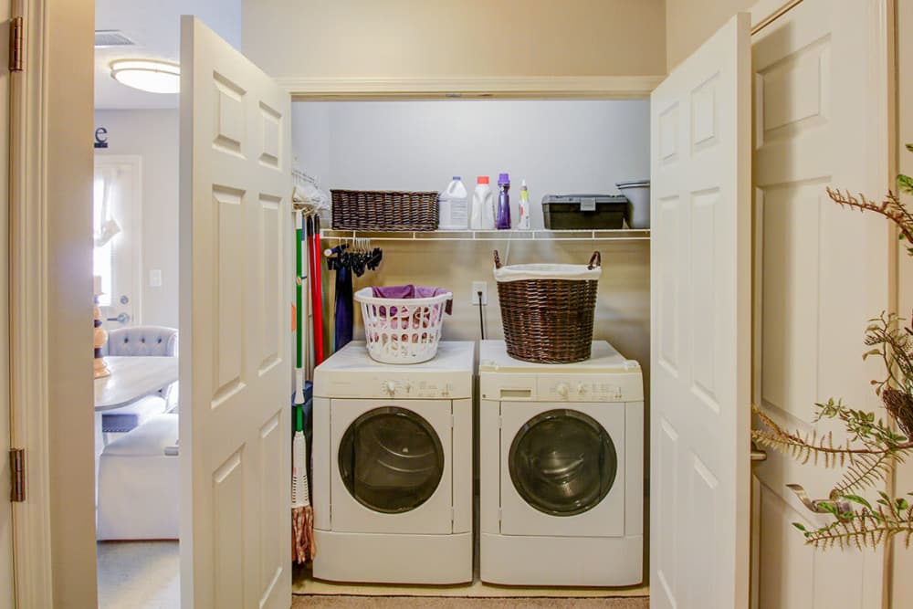 Laundry room with stacked washer and dryer, storage shelves, and organized cleaning supplies at Pennington Crossing in Johnson City, Tennessee