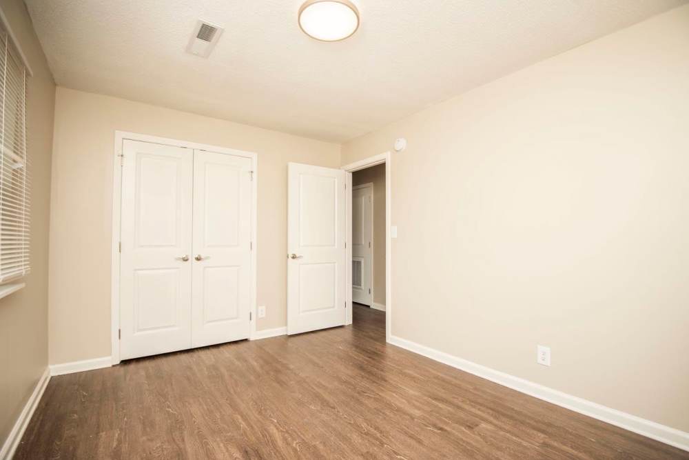 Spacious room with wood-style flooring and double closet doors, neutral walls and natural light at Plainsview Greene in Tellico Plains, Tennessee