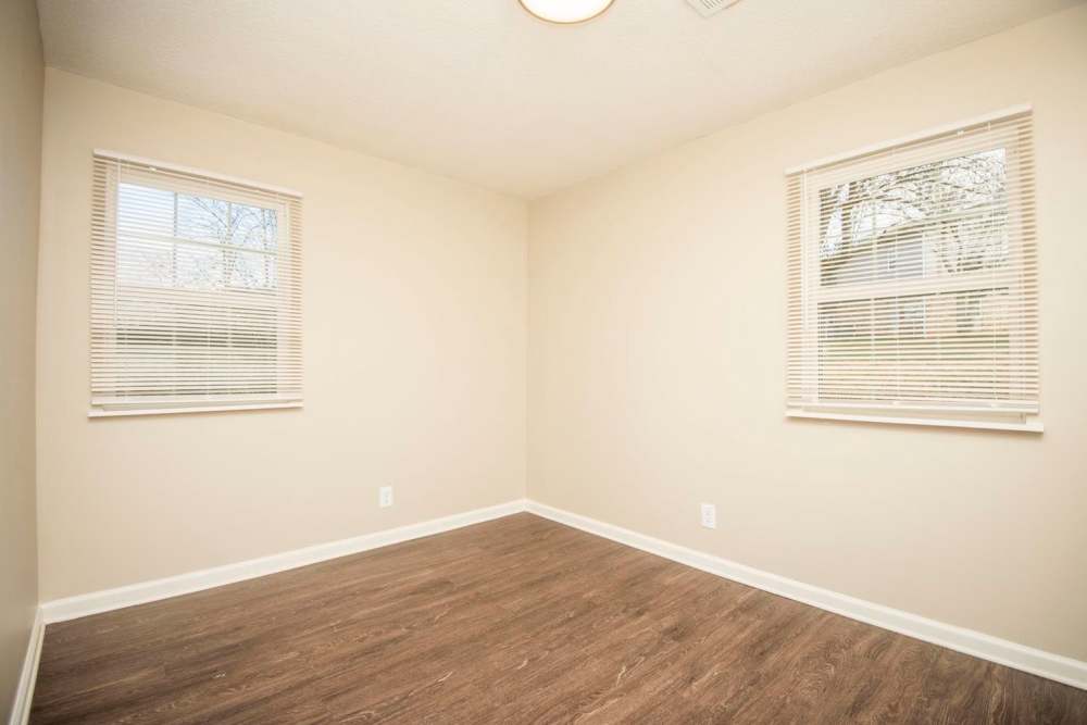 Empty room with wood-style flooring and two windows with blinds at Plainsview Greene in Tellico Plains, Tennessee