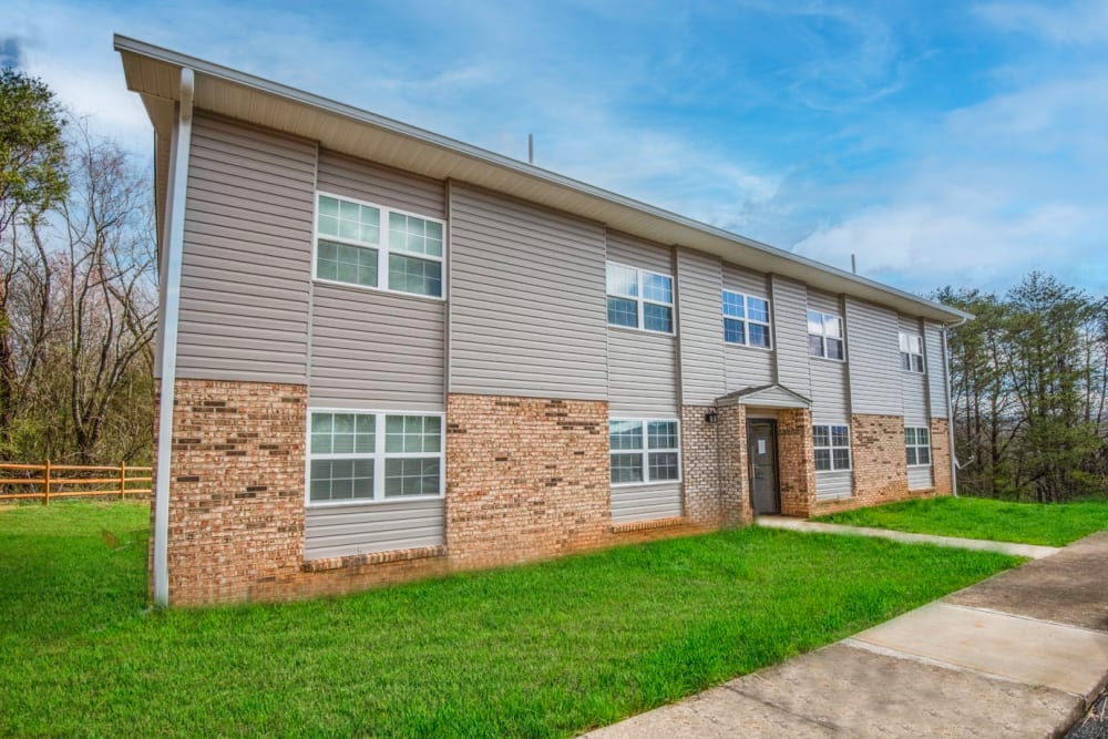 Modern apartment community with landscaped lawn and multiple large windows at Plainsview Greene in Tellico Plains, Tennessee