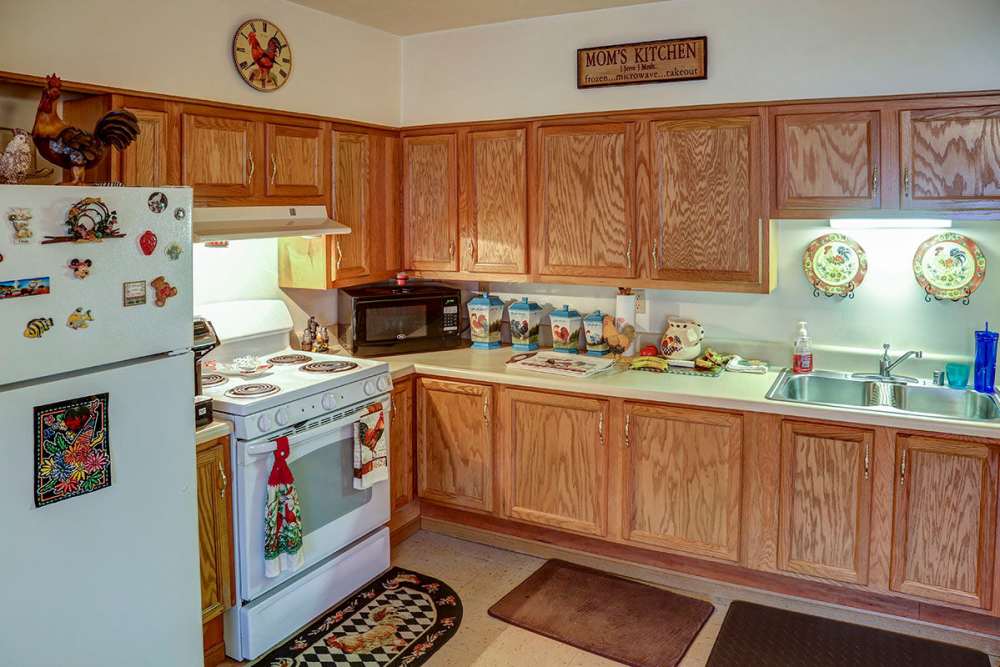 Modern kitchen with wooden cabinets, white countertops, and decorative plates on the wall at Sawgrass Greene in Grayson, Kentucky